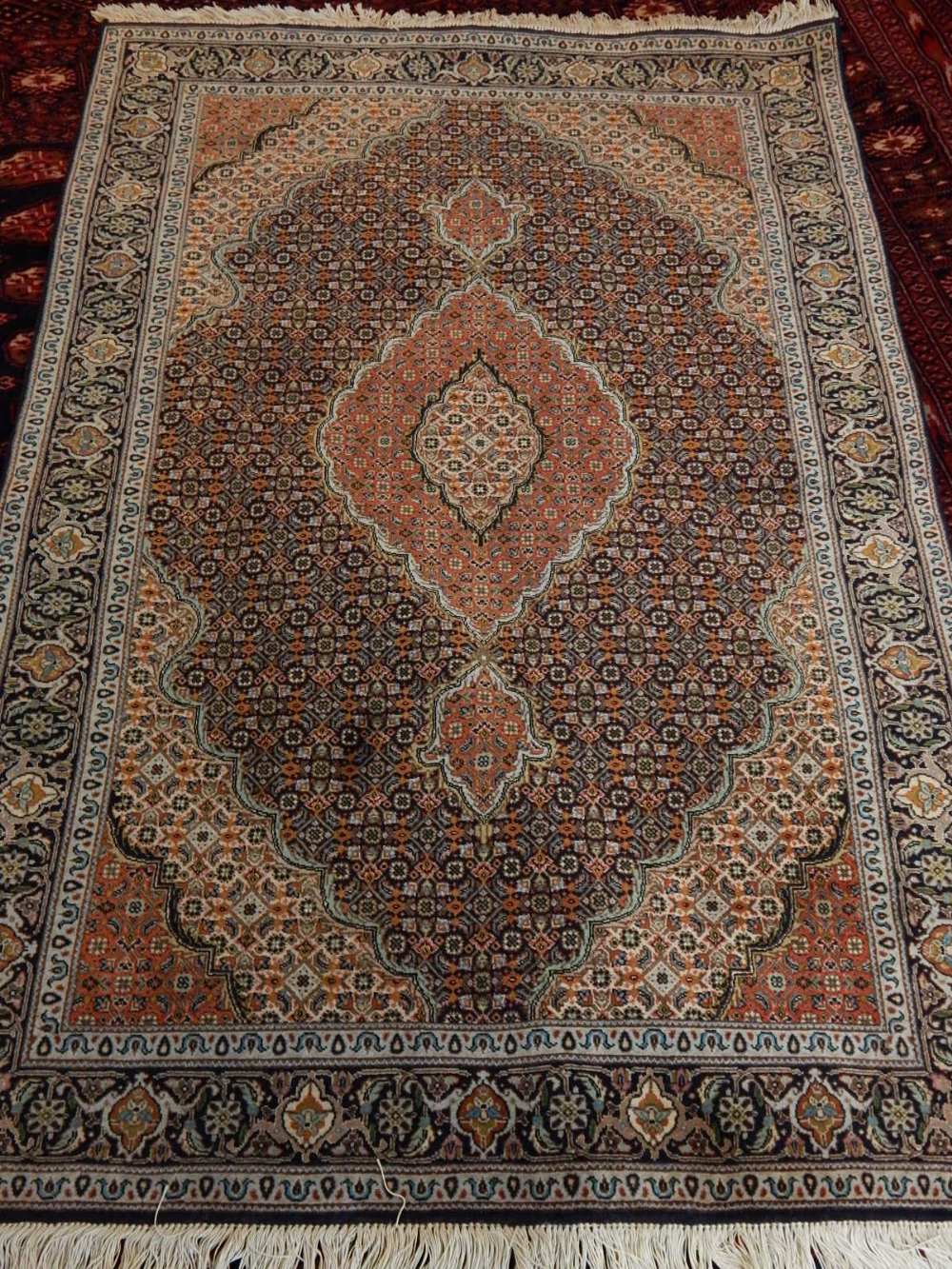 A Kashmiri rug, decorated to centre with lobed tear drop medallion, on a geometric ground,