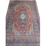 A red ground Keshan rug, decorated to centre with tear drop medallion on a foliate ground,