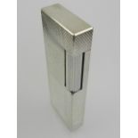 A white metal Dunhill cigarette lighter.