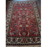 A red ground Qum rug, decorated with a continuous design of floral design,