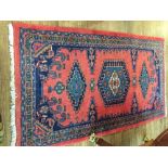 A red ground Hamadan rug, decorated with stepped medallions within stylised floral border,