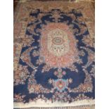 A large rug, having red and cream decoration on a blue ground, fringed.