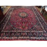 A red ground Mashad rug, decorated with floral lobed tear drop medallion to centre,