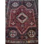 A red ground Caucasian rug, decorated with stepped diamond shaped medallions to centre,