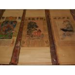 Three Chinese scrolls, decorated with various scenes and Chinese writing.