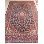 An indigo ground Keshan wool and silk rug, decorated with foliate design, fringed to one side, L.