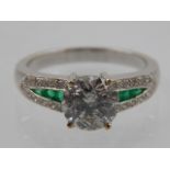 An 18 carat white gold, diamond, and emerald ring, set central round cut diamond of approx. 1.