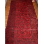 A red ground Bokhara rug, decorated with elephant medallions, within reticulated borders, L.