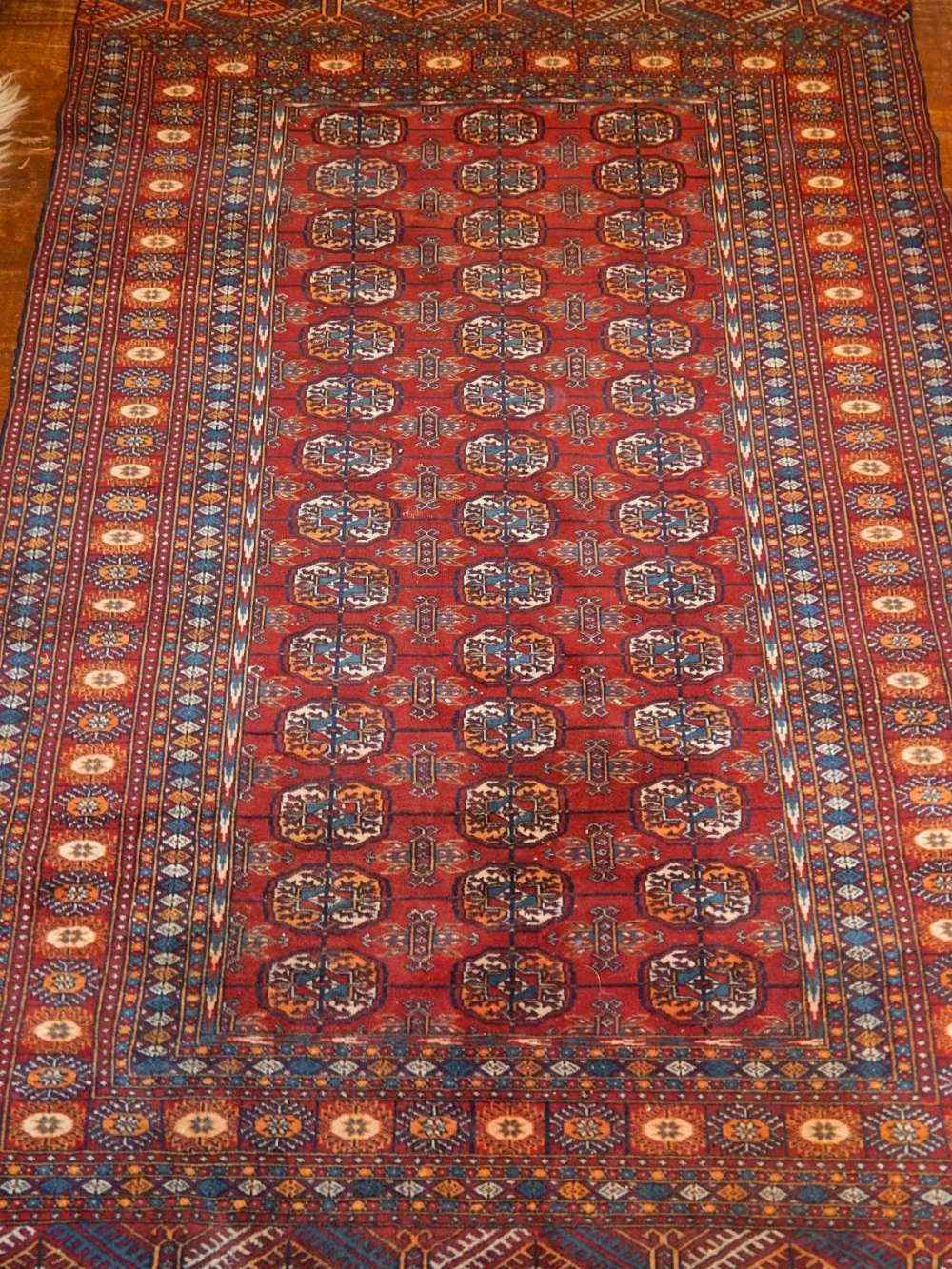 A red ground Bokhara rug, decorated with three rows of elephant medallions to centre,