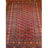 A red ground Bokhara rug, decorated with three rows of elephant medallions to centre,
