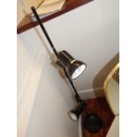 A 1980's black floor standing lamp, having adjustable twin spotlights, raised on circular base.