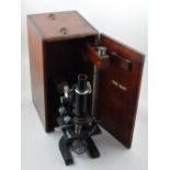 A 20th century microscope by W & J Georgel Ltd., finished in a black crackle lacquer, within a