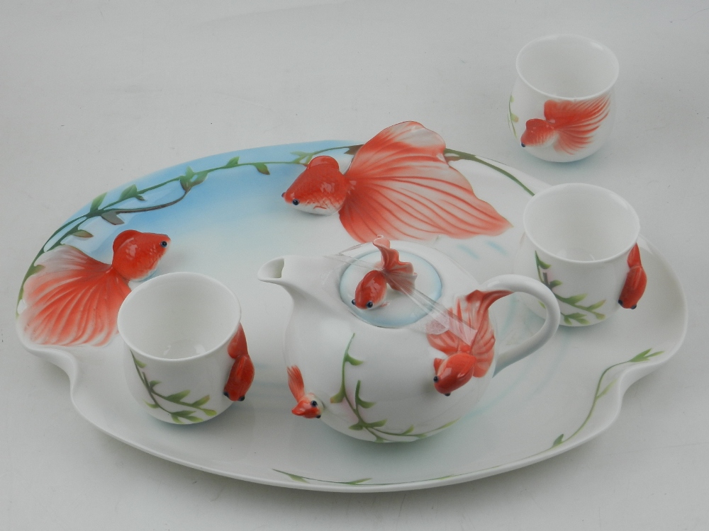 A porcelain part tea set, decorated with goldfishes, to include three cups, tea pot and tray.