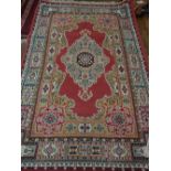 A Persian style rug, decorated with tear drop medallion to centre, within floral borders, L.