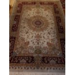 A cream ground Tabriz rug, having central floral medallion on a foliate ground,