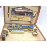 A brown leather vanity case fitted with glass bottles with blue enamel and brass lids, mirror,