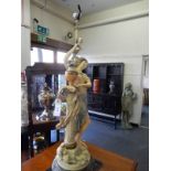 A painted metal tablelamp base in the form of a lady standing beside a column with an urn of