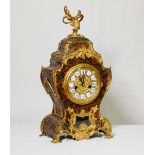A French mantel clock with circular white enamel dial, in a red Buhl case, on leaf scroll feet -