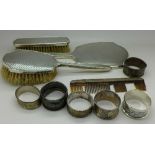 Six silver napkin rings, 86g, a silver hand mirror, two silver backed brushes and a comb,