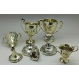 A pair of small silver candlesticks, one a/f, weighted, and four silver trophies, a/f,