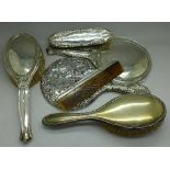 Two silver backed mirrors, three brushes and a comb,