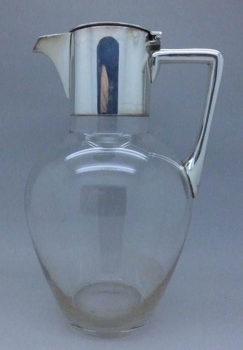A glass water jug with plated top,