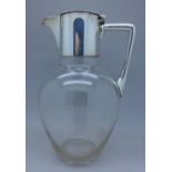 A glass water jug with plated top,