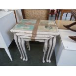 A nest of three painted stacking side tables with glass top