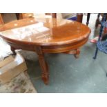 An oval coffee table with fluted square legs with X stretcher