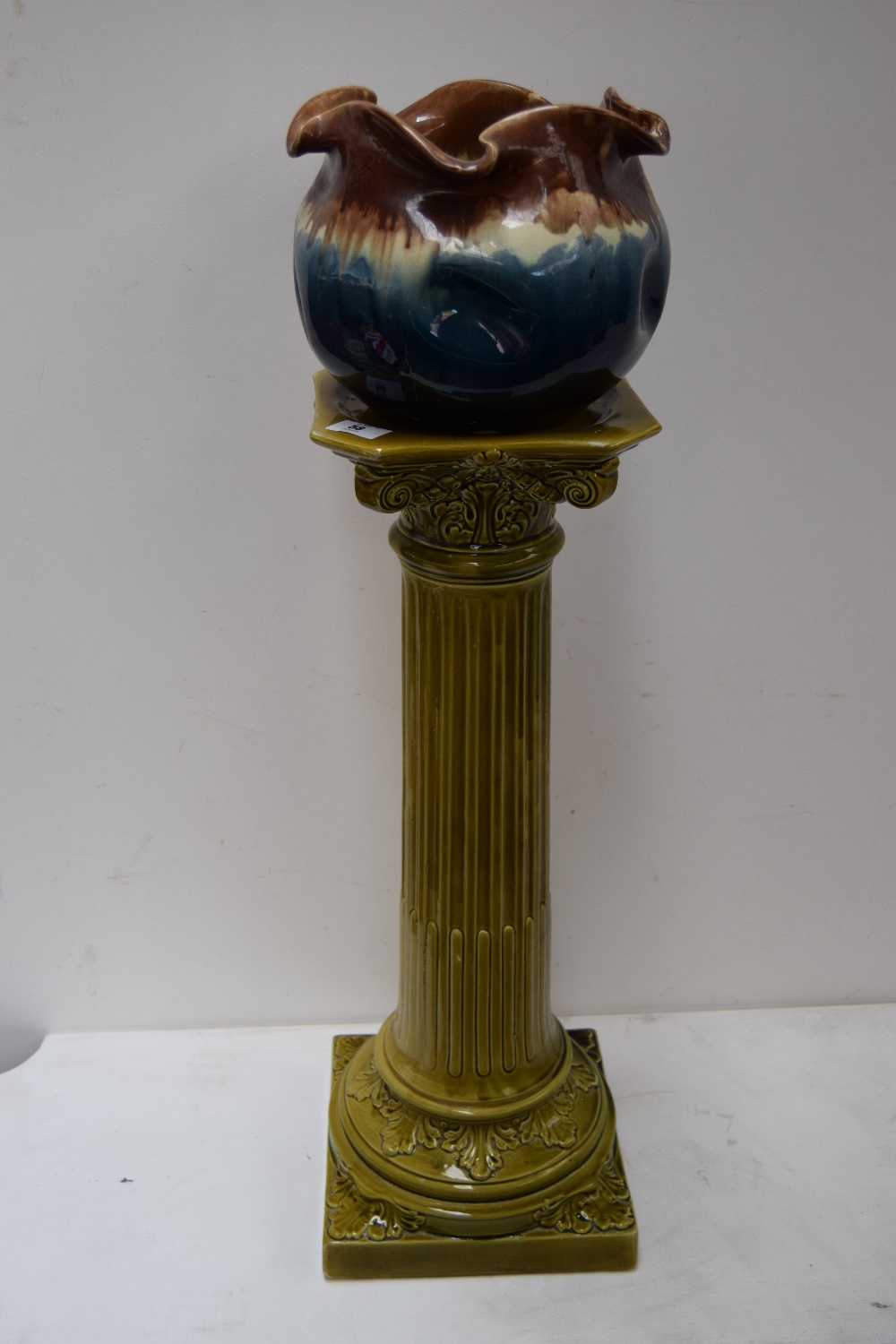 A green glazed ceramic pot stand in the form of a classical fluted column together with a brown and