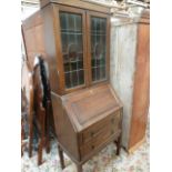 A 20th century oak bookcase over bureau, glazed doors over drop flap and two drawers,