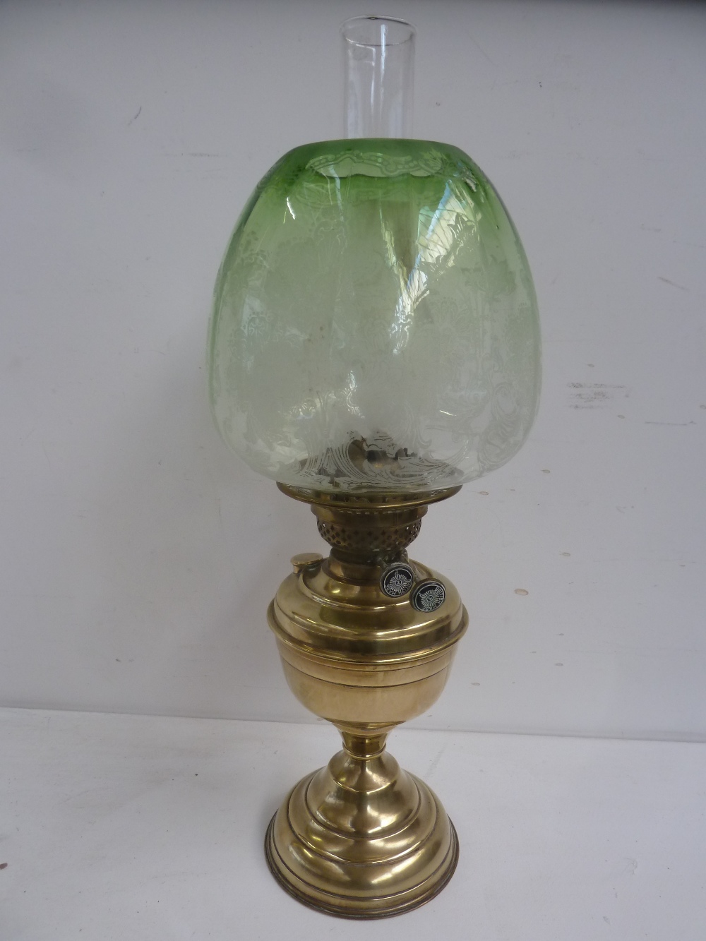 A Victorian brass oil lamp with acid etched green glass shade, and glass chimney,