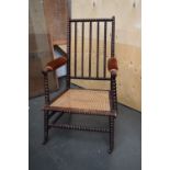 A bobbin back carver chair with turned supports and a wicker seat on castors