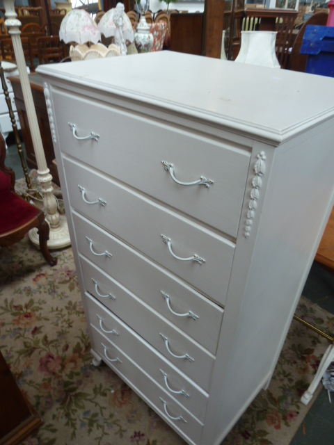A white painted chest of drawers with six graduating drawers