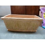 A rectangular terracotta planter decorated with ferns,