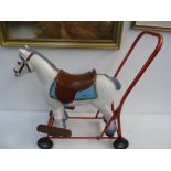 A Triang carpet toy horse on wheels with red painted handle