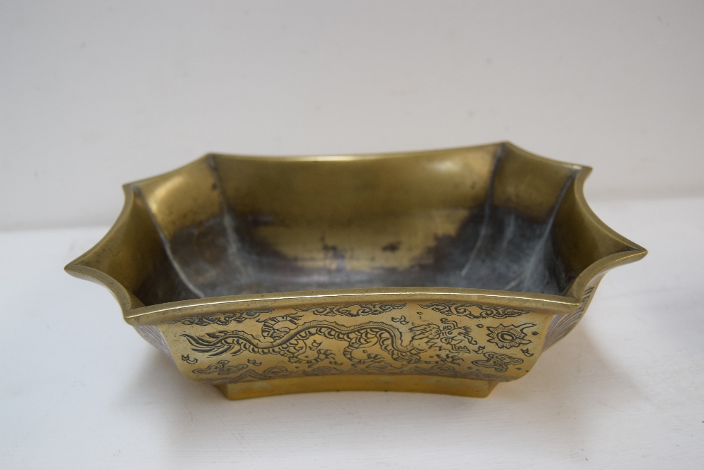 A Chinese brass bowl of serpentine form, decorated with foliage and dragons, stamp to base,