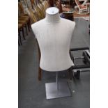 A linen covered half torso mannequin in metal stand