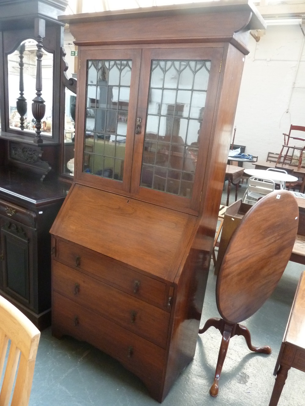 An Arts and Craft oak bookshelf over bureau, glazed doors over three long drawers with carved apron,