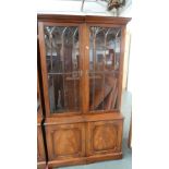 A pair of bookshelves over cupboard, glazed doors,