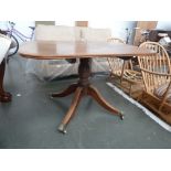 A Regency walnut tip top dining table on multi turned stem and four splayed legs with lion paw feet