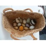 A wicker bag with a collection of onyx and stone eggs and balls and other items