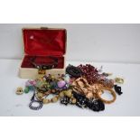 A collection of various pieces of costume jewellery with a cream jewellery box