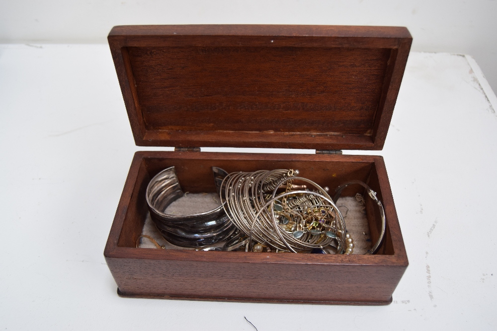 A wooden box of jewellery to include white metal rings, bracelets, necklaces,