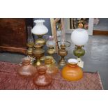 A number of oil lamps, some modified, with glass shades,