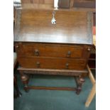 An oak bureau with a carved fall flap and apron with geometric decoration opening to reveal a