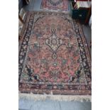 A rug with red fields and floral borders and cream fringing 213 x 140cm
