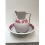A ceramic wash bowl and jug with banded pink design heighten in gilt on cream ground together with