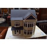 A large modern painted dolls house with four rooms and an attic room fitted with carpets and