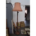 An oak standing lamp with turned base and pink shade 190cmH